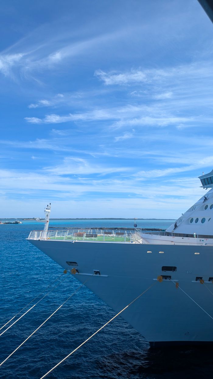 creative-03 A cruise ship sailing in the ocean under a bright blue sky, displaying a serene seascape.